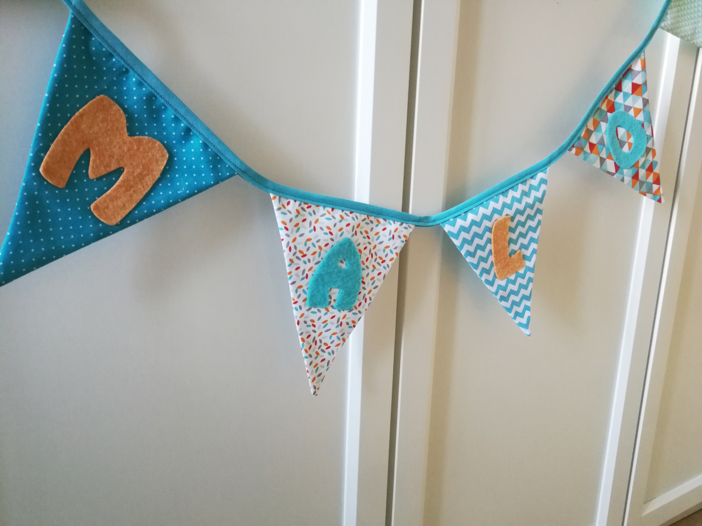 Guirlande de fanions en tissus (bleu turquoise, orange, gris et rouge) et personnalisable avec prénom